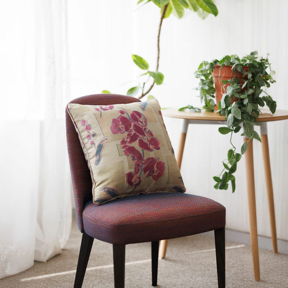 ゴールド色の幾何学模様のベースに濃色のピンク色の凛とした胡蝶蘭が際立つクッションはラグジュアリーな雰囲気が漂います